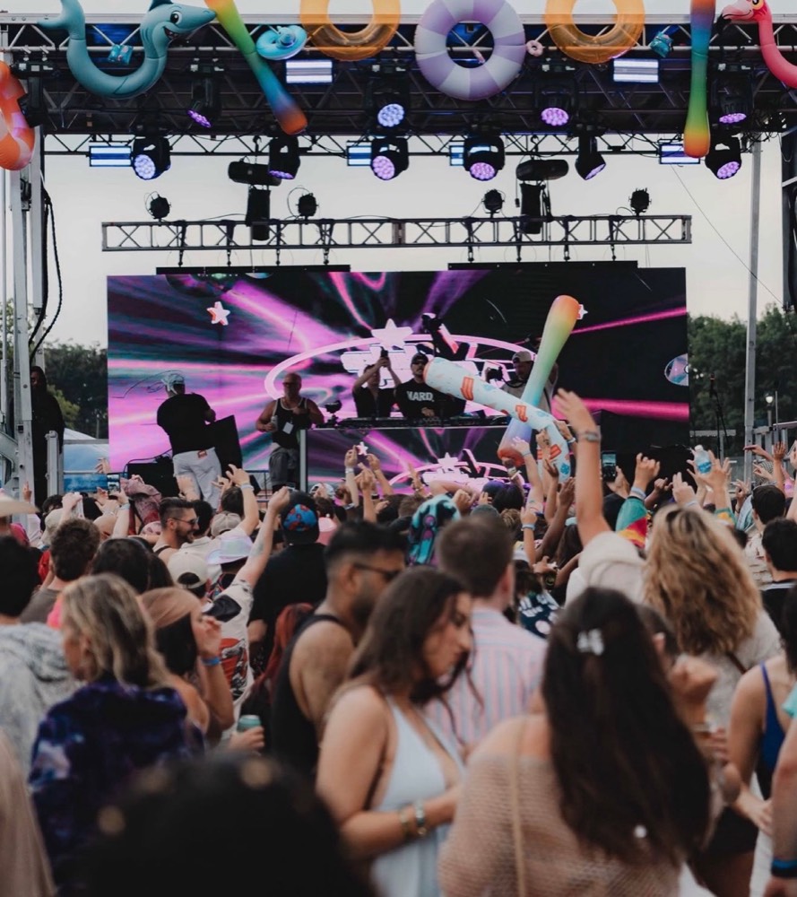 Festival crowd with inflatables in front of a DJ stage