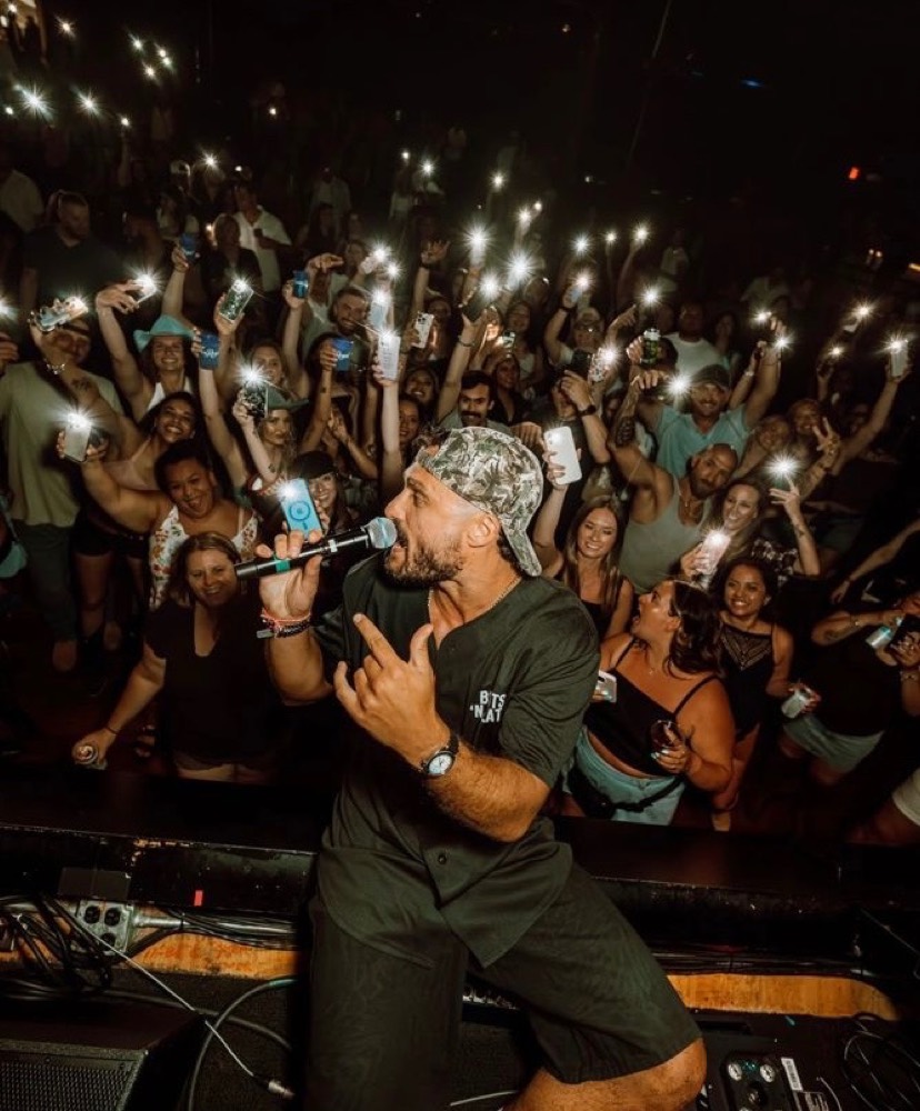Performer on the mic with fans holding up phone lights