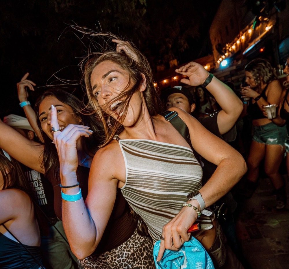 People dancing in a crowd at an outdoor party at night